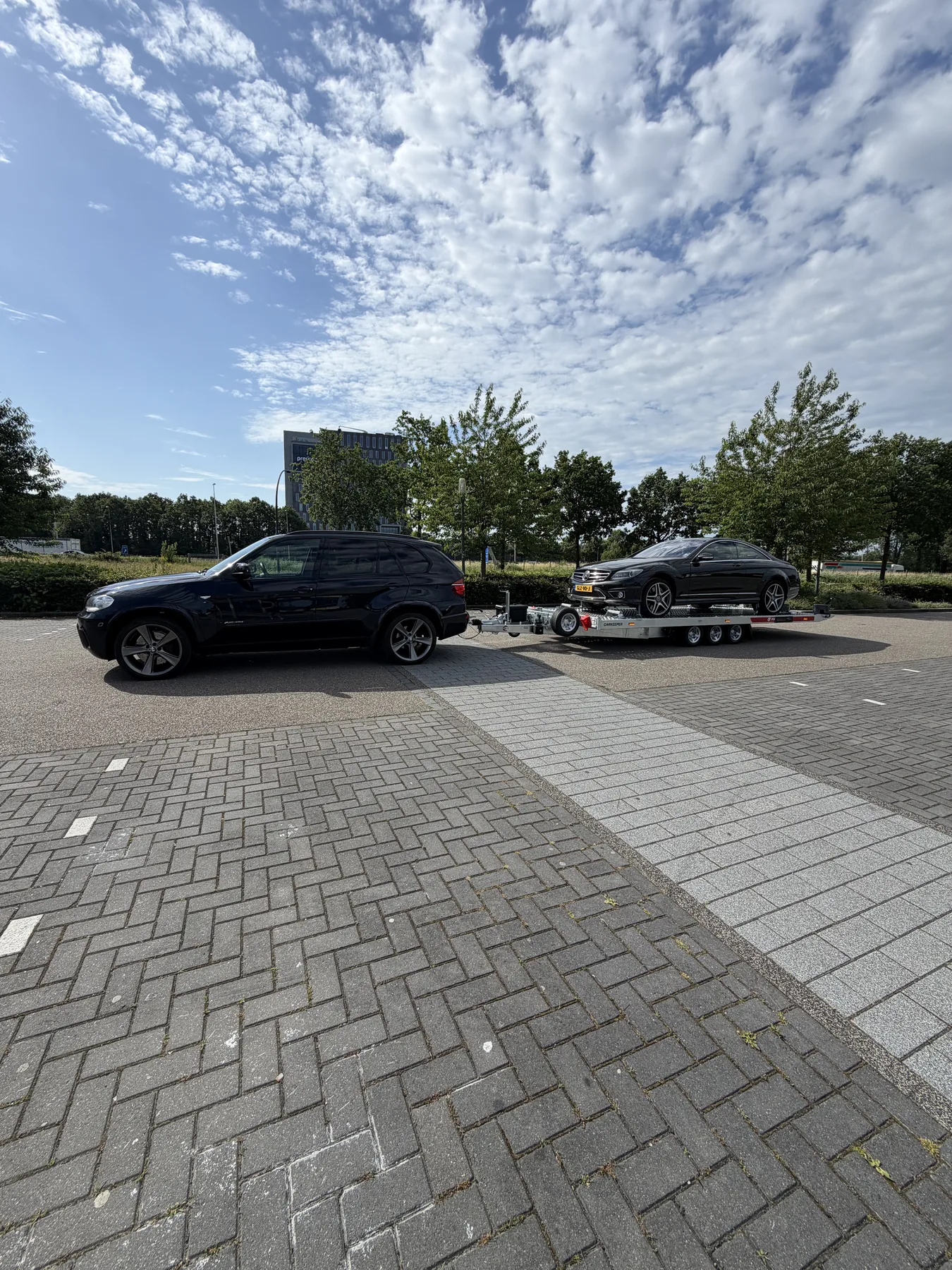 Zwarte Mercedes CL op Temared dieplader achter BMW X5 — particulier autotransport vanuit Hengelo door Zorgeloos Autotransport